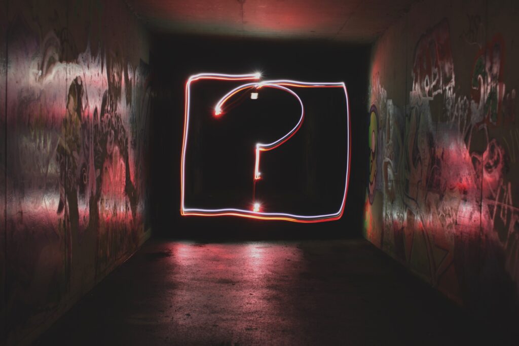 A question mark made of neon lights appears at the end of a dark tunnel. 