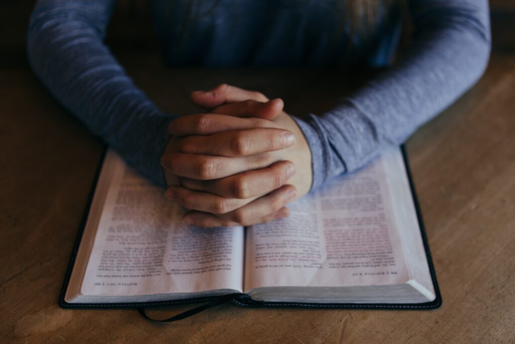 Decorative. Clasped hands rest over a bible.