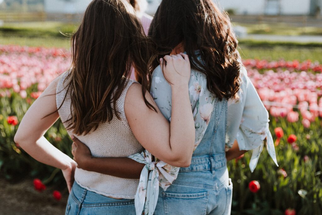 Decorative. Two teenage girls stand with their arms around each other.