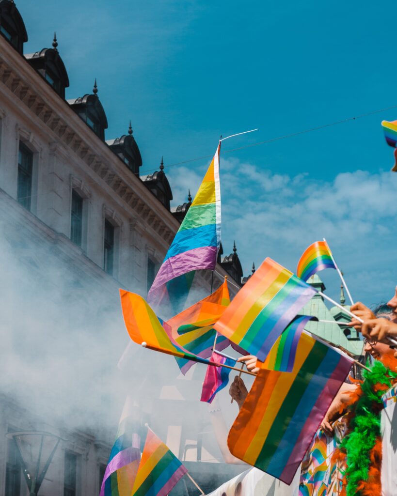 Decorative. Several people wave hand held Pride flags. 