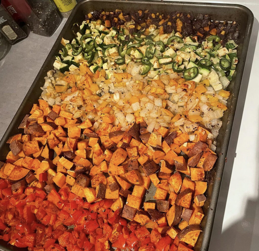 A baking sheet holds veggies in a rainbow. 